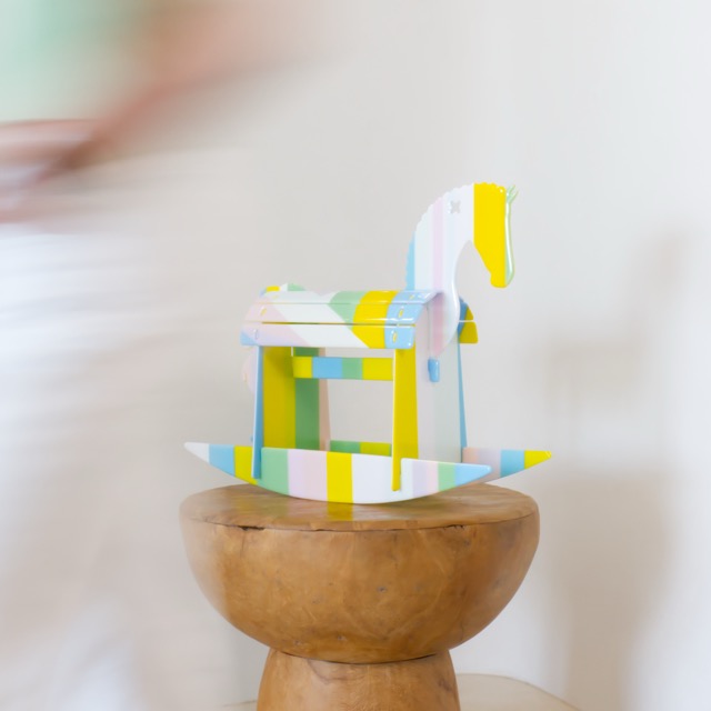 Motion-blurred shot of someone walking past the rocking horse, sculpture sharp and still